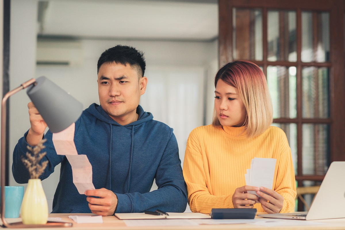 Young Stressed Asian Couple Managing Finances, Reviewing Their B