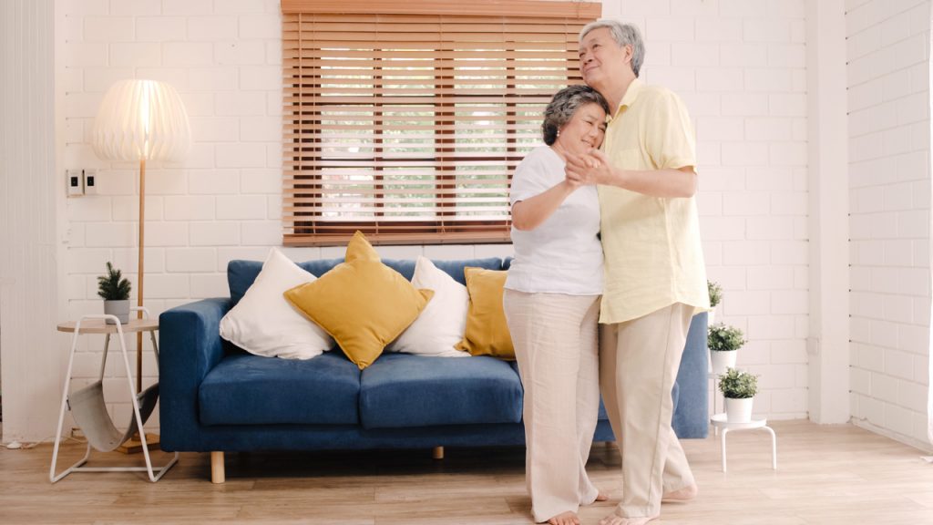 An elderly couple dancing in their living room