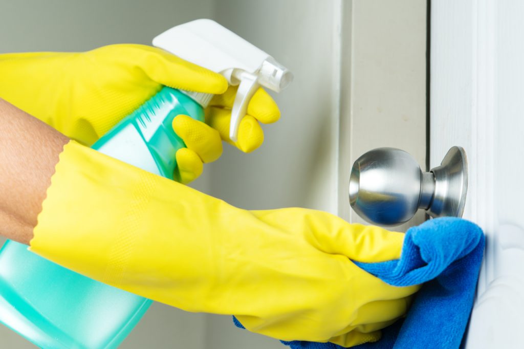 A person disinfecting a door knob